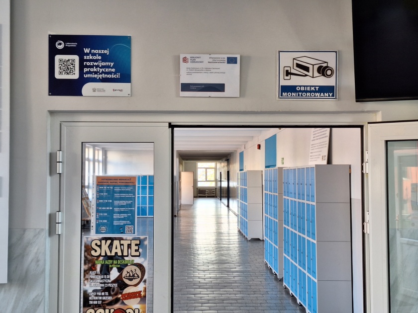 Wejście do szkoły z tablicą promującą projekt